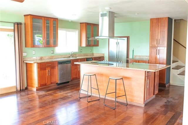 kitchen with island range hood, dark wood-type flooring, a sink, dishwasher, and brown cabinetry