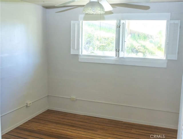 empty room with baseboards, dark wood-style floors, a wealth of natural light, and a ceiling fan