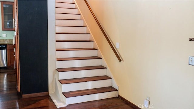 stairway with wood finished floors and baseboards