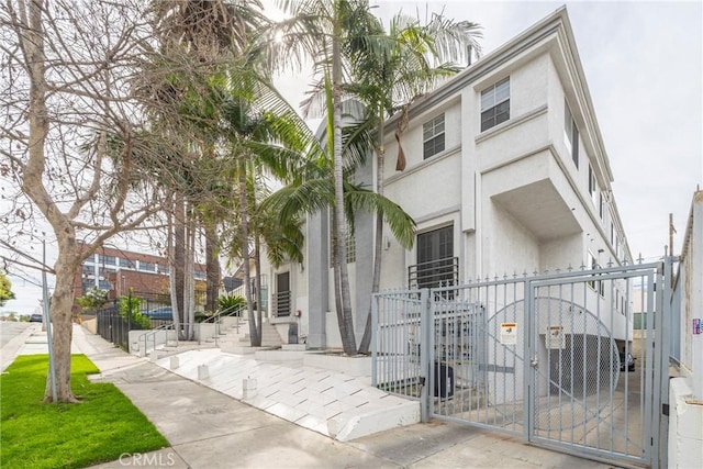 view of front of house with entry steps, a gate, fence, and stucco siding