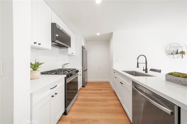 kitchen with appliances with stainless steel finishes, light countertops, white cabinets, and a sink