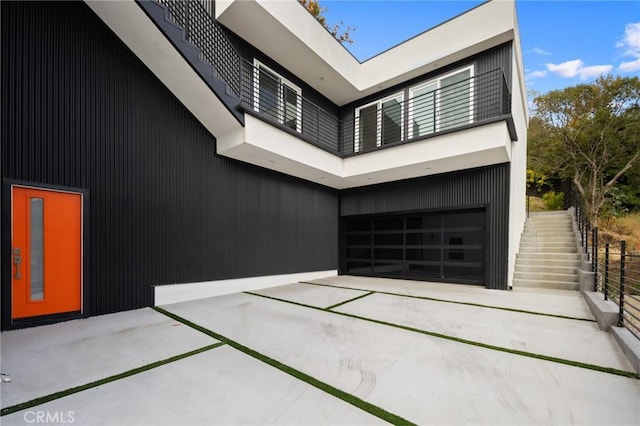 view of home's exterior with a garage, a patio, driveway, and stairs