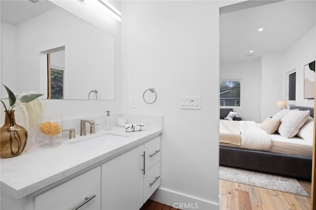 bathroom with vanity, baseboards, wood finished floors, and ensuite bathroom