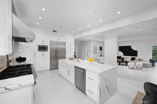 kitchen featuring visible vents, built in appliances, marble finish floor, a sink, and exhaust hood