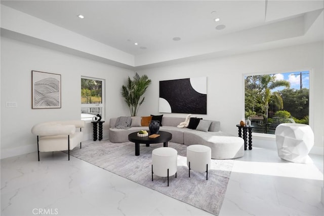 living room featuring marble finish floor, plenty of natural light, a raised ceiling, and recessed lighting