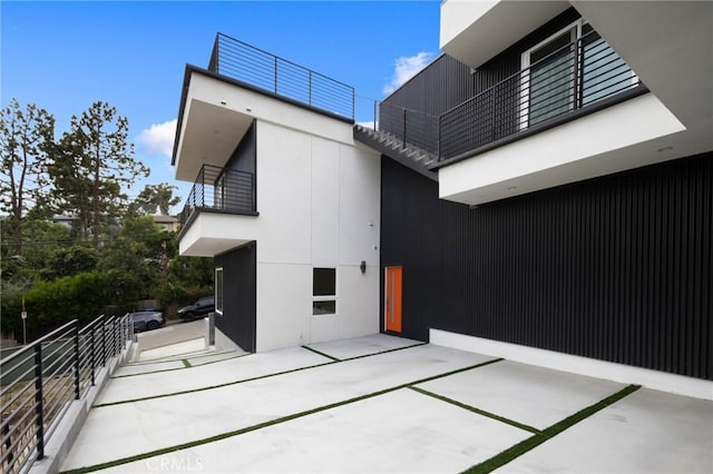 view of property exterior with a patio area, a balcony, and stucco siding