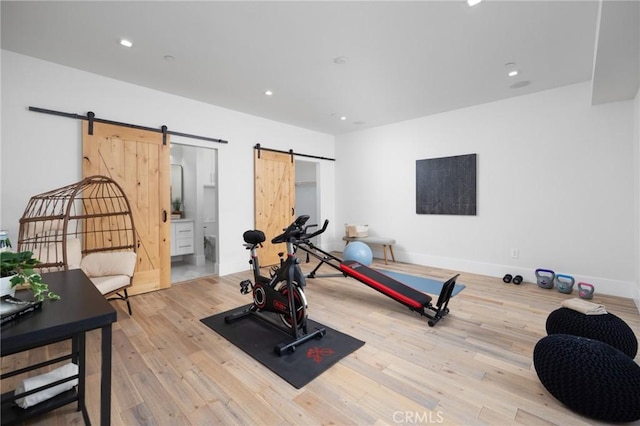 workout room with recessed lighting, wood finished floors, and a barn door