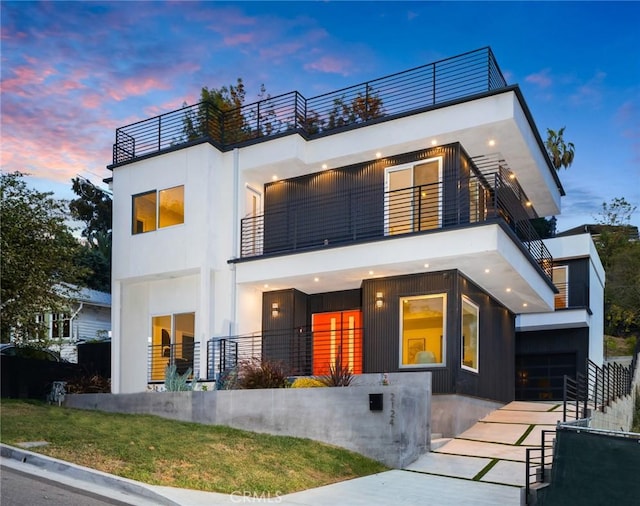 modern home with a garage, driveway, a balcony, and stucco siding