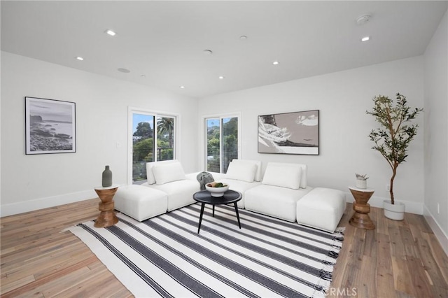 living room featuring recessed lighting, baseboards, and light wood finished floors