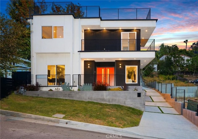 view of front facade featuring a balcony, fence, and stucco siding