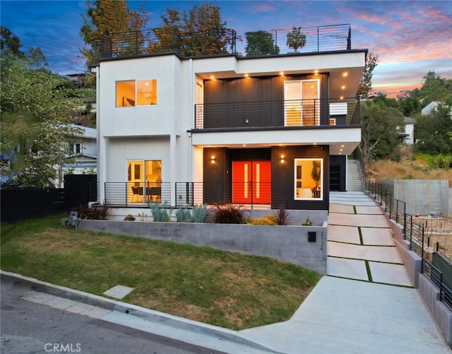 rear view of house featuring french doors, a lawn, a balcony, and stucco siding