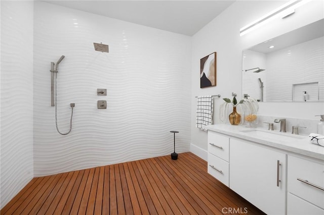 bathroom featuring wood finished floors, walk in shower, and vanity