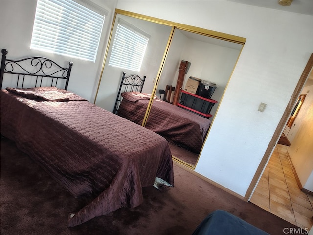 bedroom featuring carpet floors, tile patterned flooring, a closet, and baseboards