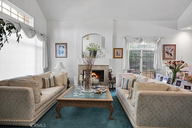 carpeted living area with vaulted ceiling and a glass covered fireplace