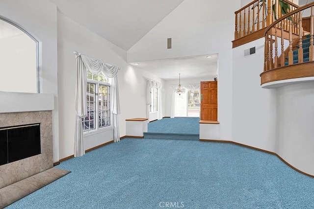 carpeted living room with visible vents, an inviting chandelier, a glass covered fireplace, high vaulted ceiling, and baseboards