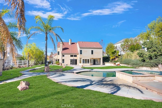 rear view of property with an in ground hot tub, a tile roof, a lawn, a chimney, and a patio area