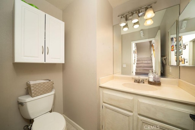 half bath featuring baseboards, vanity, and toilet