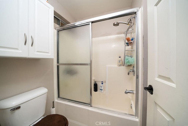 bathroom with toilet and shower / bath combination with glass door