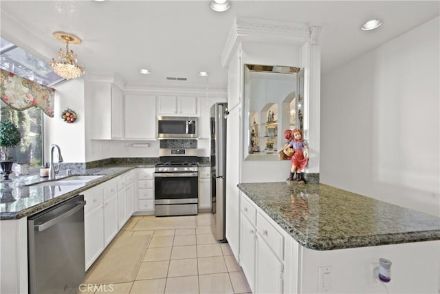 kitchen featuring a peninsula, appliances with stainless steel finishes, a sink, and white cabinets