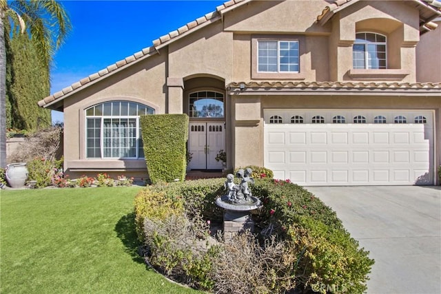 mediterranean / spanish home featuring a garage, a front yard, concrete driveway, and stucco siding