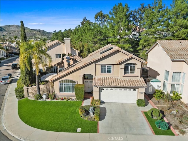 mediterranean / spanish-style home with stucco siding, a front yard, a mountain view, driveway, and a tiled roof