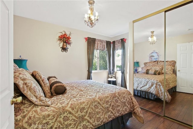 bedroom with a closet, wood-type flooring, and an inviting chandelier