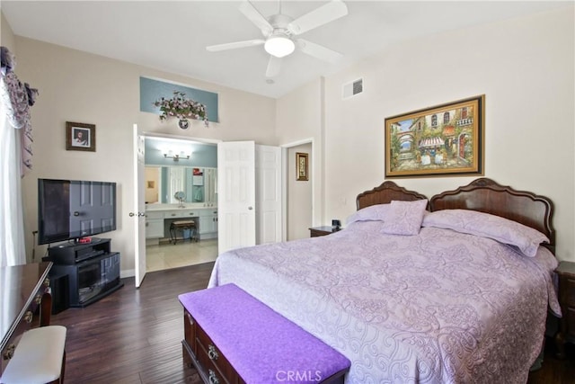 bedroom featuring ensuite bathroom, visible vents, baseboards, a ceiling fan, and dark wood finished floors