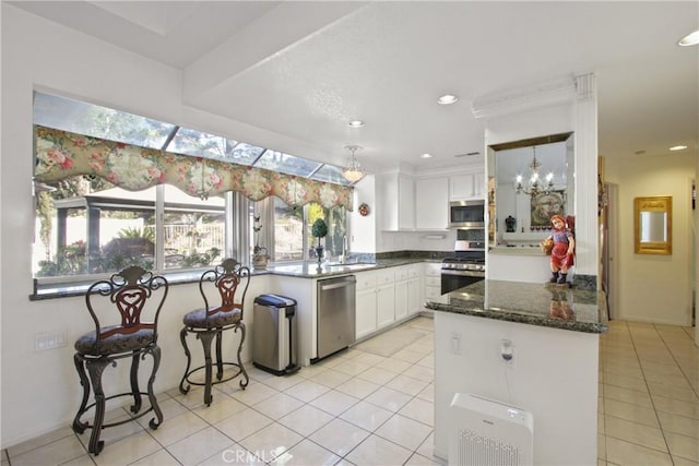 kitchen featuring dark stone countertops, appliances with stainless steel finishes, light tile patterned flooring, and white cabinetry