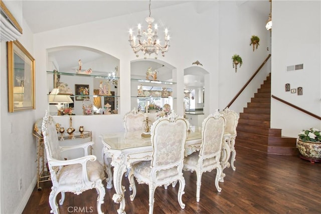 dining room with visible vents, stairway, wood finished floors, an inviting chandelier, and vaulted ceiling