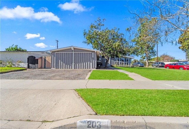 mid-century home featuring driveway, a front lawn, and a gate