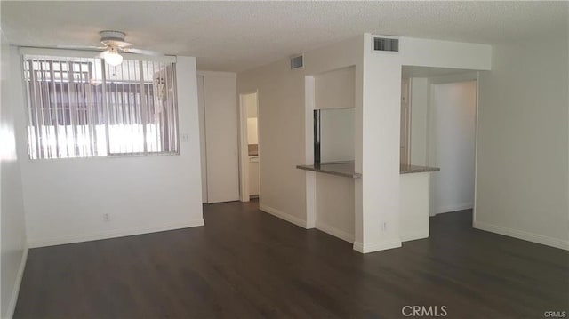 empty room with visible vents, a textured ceiling, baseboards, and wood finished floors