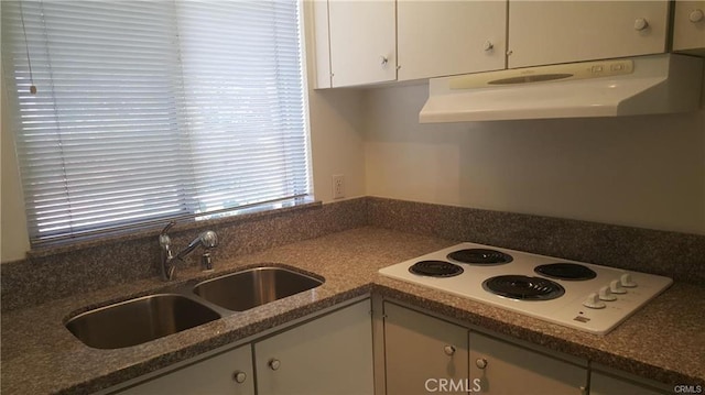 kitchen with dark stone counters, white electric cooktop, ventilation hood, white cabinetry, and a sink