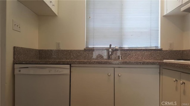 kitchen featuring white dishwasher, a sink, and white cabinets