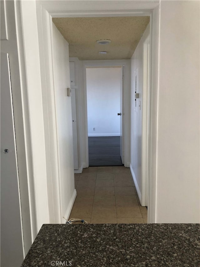 corridor featuring baseboards and light tile patterned floors