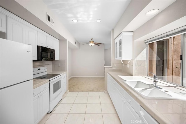 kitchen featuring white appliances, a sink, visible vents, white cabinetry, and tile counters