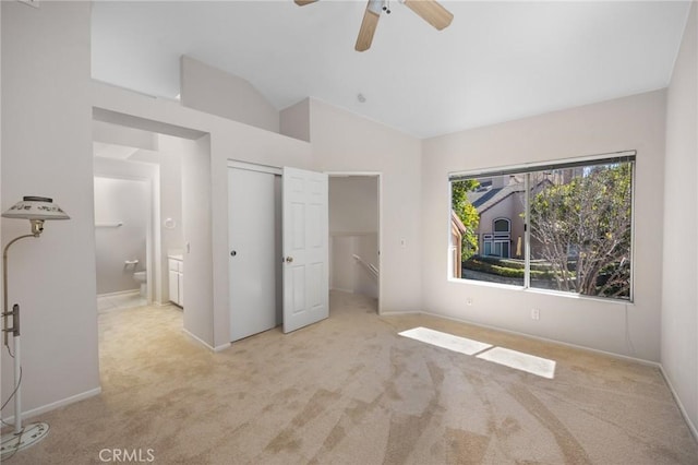 unfurnished bedroom featuring vaulted ceiling, a closet, carpet, and ensuite bathroom