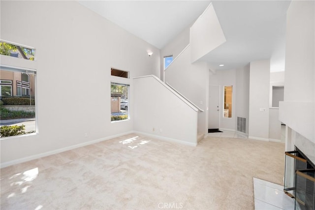 unfurnished living room featuring carpet floors, high vaulted ceiling, visible vents, and baseboards