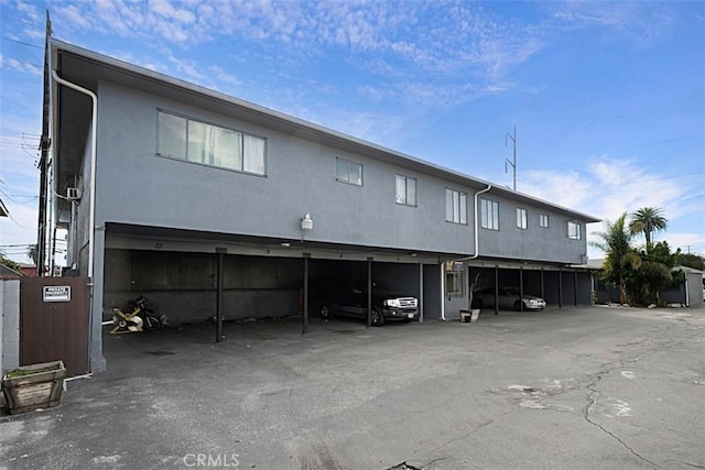 back of property with covered parking and stucco siding