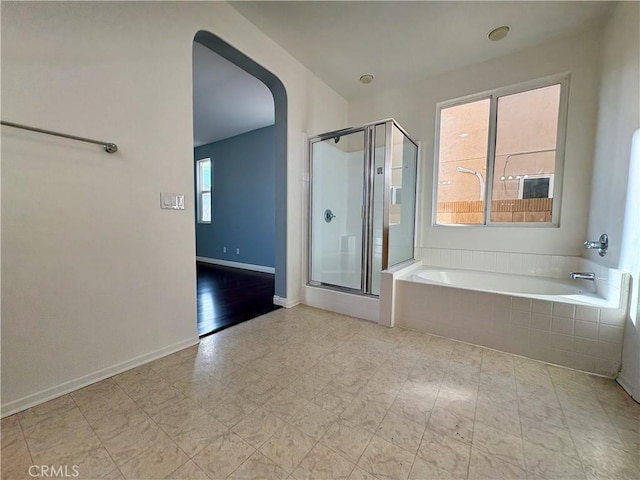 full bathroom with a garden tub, a shower stall, and baseboards