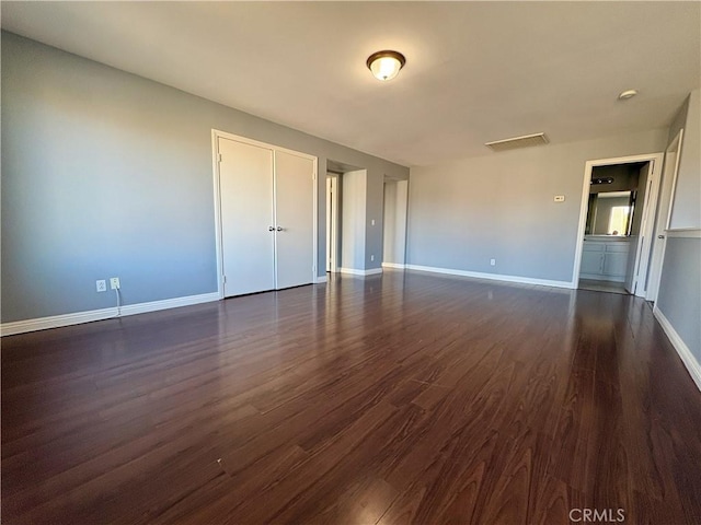 unfurnished room featuring dark wood-type flooring, visible vents, and baseboards