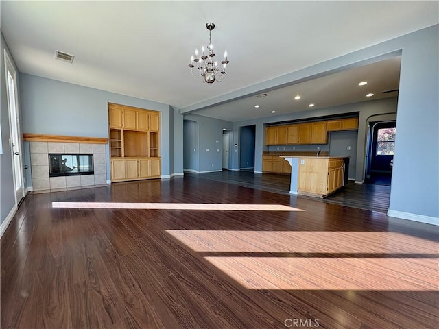 unfurnished living room featuring a fireplace, dark wood finished floors, visible vents, and baseboards