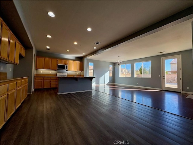 kitchen with visible vents, stainless steel microwave, open floor plan, dark wood-type flooring, and an inviting chandelier