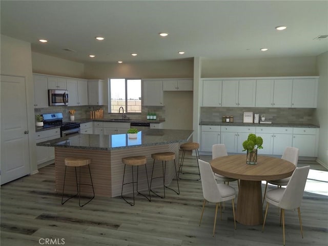 kitchen with stainless steel appliances, light wood-type flooring, a sink, and white cabinets