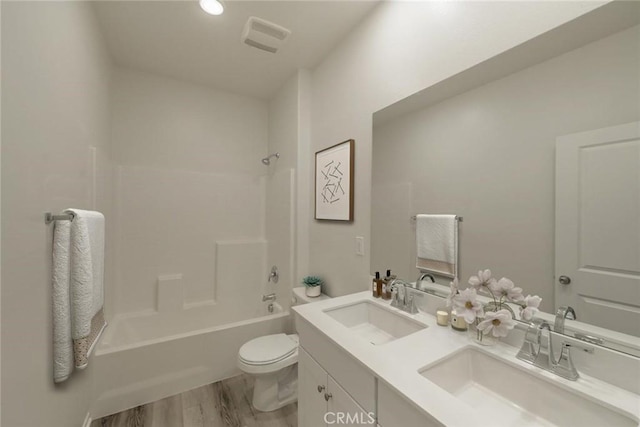 bathroom with toilet, double vanity,  shower combination, and a sink