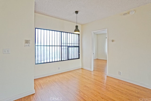 unfurnished room featuring light wood-type flooring, baseboards, and a textured ceiling