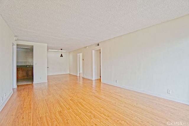 spare room featuring a textured ceiling, light wood finished floors, and visible vents