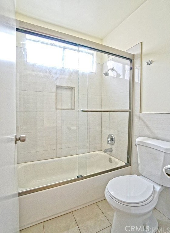 bathroom featuring toilet, shower / bath combination with glass door, and tile patterned flooring