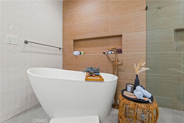 bathroom with a freestanding bath and tile walls