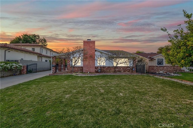 view of front of house with brick siding, fence, a chimney, and a front lawn