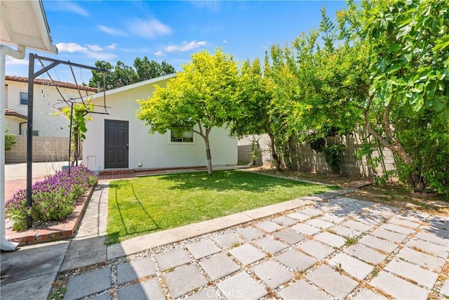 back of house featuring stucco siding, fence, and a yard